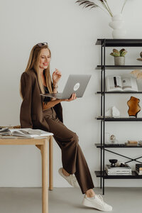 kaboompics_young-entrepreneur-dressed-in-brown-suit-holds-laptop-video-call-27943