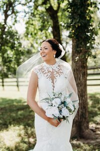 Bride smiling outdoors with bouquet on the grounds of Bradshaw Duncan House, a top venue near Louisville, Kentucky.