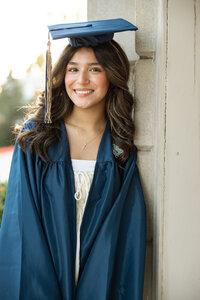 High school graduate smiling in cap and gown during an outdoor graduation portrait session by Kaitlyn Dawn Photography.