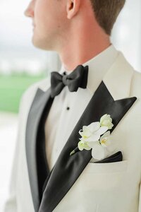 groom in white suit orchids