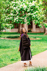 Vanderbilt Master's graduate wearing attire on sidewalk smiling at camera