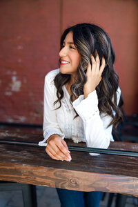 High school senior girl looking to the side while leaning on a wooden railing, natural light senior portrait by Kaitlyn Dawn Photography.