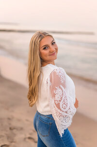 A Waukesha North High School senior stands on the beach of Lac La Belle looking over her shoulder at the camera.