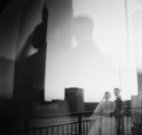 Artistic black and white film portrait of a bride and groom reflected in glass during their Huntsville wedding.