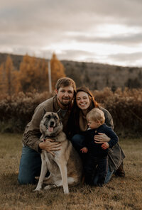 Mom and dad and son posing at golden hour in New England. Fine art family photography capturing playful and intimate connection outdoors.