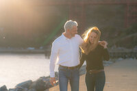 couple walking sunset engagement photos by the bay and golden gate bridge at cavallo point