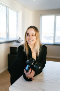 Branding fotografie van fotografe met camera in hand leunend op een tafel