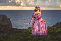 Young girl in pink gown standing on coastal cliffs at sunset in Eastern North Carolina