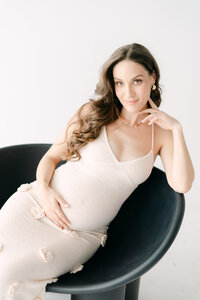 Expecting mother holding bump in minimalist Miami studio, maternity photographer
