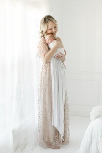 A mother holds her newborn baby in Nashville Portrait Photographer Kristie Lloyd's all white studio