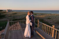 Bride and Groom stand on rooftop of Nantucket home with Atlantic Ocean behind them.