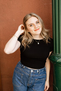 High school senior girl standing against a textured wall in natural light, casual senior portrait by Kaitlyn Dawn Photography.