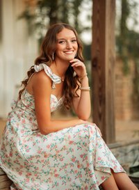 Senior portrait in downtown Magnolia Springs, Alabama — posing on some steps in front of a cozy cottage.