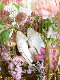 close-up of bridal shoes and gown details with lilac installation softly visible in the background