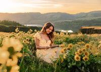Girl sitting up at Tom McCall Nature Preserve in Rowena. Wild Sunflowers all around her reading a journal. Senior Portraits.