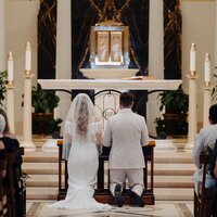 Bride and groom kneel in front of altar at their nuptial mass wedding