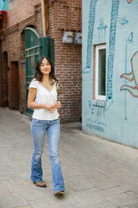 High school senior girl standing in an alleyway with colorful mural walls, lifestyle senior portrait captured by Kaitlyn Dawn Photography.