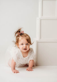 Charleston Cake Smash Photographer- Baby looks into the camera during Milestone Portraits at Holy City Babies Portrait Studio in Charleston, SC.