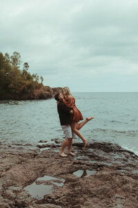 a couple kissing on the rocks of lake superior