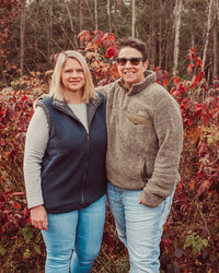Kristina and Tiffany standing outside in front of orange fall foliage