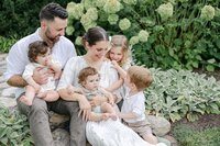 large family sitting on steps with hydrangeas in background