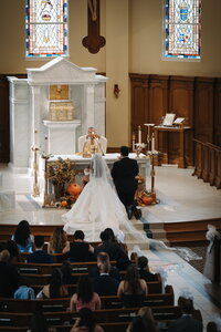 Catholic priest raising Eucharist for bride and groom