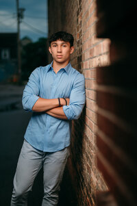 A senior student from Germantown High School leans again a weathered brick wall in Sussex, WI after dark.