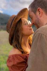 intimate couple engagement photos in open field by water tower and mountain in bay area california