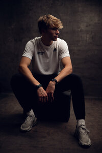 An athletic student from Arrowhead High school poses for his senior portraits in a shadowy section of our Waukesha photo studio.