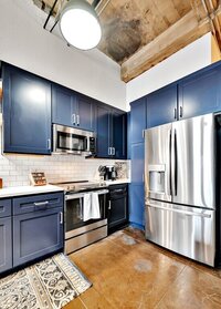 Kitchen with stainless steel appliances in this three-bedroom, two-bathroom industrial modern loft condo in the historic Behrens building in downtown Waco, TX.