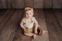 baby in cream lace outfit with wooden texture background during fine art studio milestone session in Los Angeles