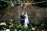 colourful and candid wedding photography at cockington court capturing bride and groom sharing a moment infont of wall