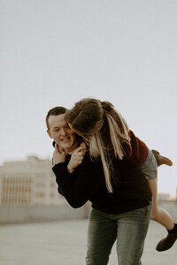 Man holding his fiance on his back and smiling