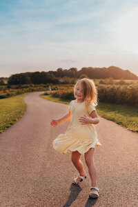 Young girl in a yellow dress twirling on a path during a Cleveland family photography session