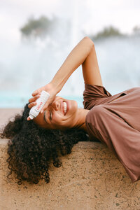 Model reclining poolside with Evian facial spray, backlit in soft afternoon light