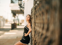 Senior portrait in downtown Foley, Alabama — waist-up with her back against a black iron fence.