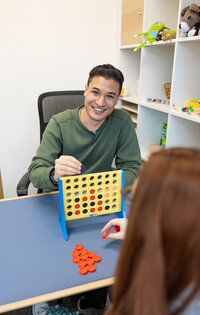 A-Baltimore-therapist-smiles-while-playing-boardgames-during-his-branding-photoshoot-with-Ingrid-Berrios-Photography
