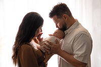 New parents kiss their newborn baby boy during his newborn session at Jennifer Brandes Photography.