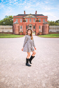Candid photo of Young girl in leopard print dress posed in front of historic brick architecture