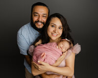 Parents holding their newborn baby during a studio family portrait session with newborn photographer Kaitlyn Dawn Photography.