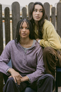 Two models in lavender and chartreuse brushed knits against a picket fence