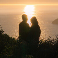 golden hour cliffside in san francisco couple on cliffside standing in sunlight by ocean
