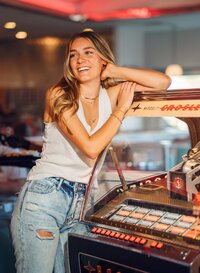 Senior portrait at Sunliner Diner in Gulf Shores, Alabama — waist-up by the jukebox, looking to
the side and laughing.