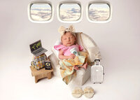 Newborn baby sleeping with her luggage on an airplane in the sky.