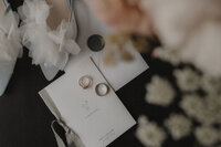 Flat lay de détails de mariage incluant les alliances, la papeterie, et les chaussures de la mariée, capturé avec soin et élégance par Jeff Gagnon photographe.