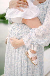 Details of toddler sitting on her mom's belly during their MIami maternity photoshoot