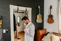 Groom getting ready at home in the Los Angeles area with natural window light and documentary wedding photography style.