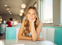Senior portrait at Sunliner Diner in Gulf Shores, Alabama — close-up smiling with her hand
resting on her face.