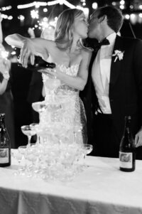 Bride pours champagne over a tower of glasses