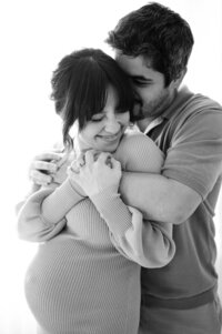 Expecting couple hugging during at home maternity session in Brickell